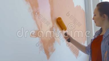 单身生活方式概念。 年轻快乐的女人用滚筒把墙壁涂成橙色