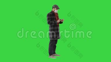 男人穿着战衣，戴着保护面具，用消毒剂在绿色屏幕上洗手，Chroma键。