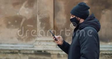 人行走和使用智能手机在社交网络中交流的侧面视图。 穿着黑棉衣服的男人