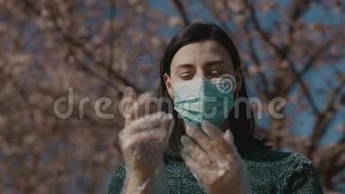 美丽悲伤的年轻女子双手戴着塑料透明手套矫正手术面罩，站在樱花