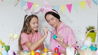妈妈和她的小女儿画鸡蛋。 为复活节做准备的幸福家庭。