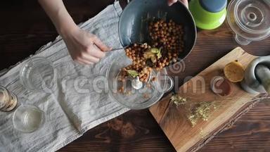一个年轻的女孩把鹰嘴豆和其他原料从碗里放进搅拌机里做自制的鹰嘴豆。 特写镜头。 视图