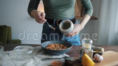女孩把调味料和鹰<strong>嘴</strong>豆放在碗里。 在家煮传统的鹰<strong>嘴</strong>豆泥。 特写
