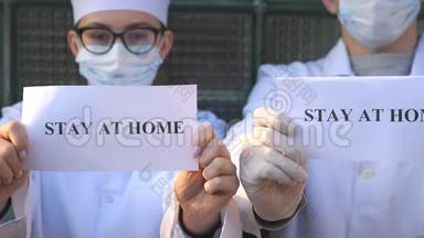 在冠状病毒流行期间，男医生和女医生正拿着一张铭文留在家里的照片。 医药