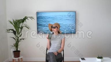 家里的女人假装在海滩上。 电视屏幕。 2020年夏季检疫旅行。 呆在家里