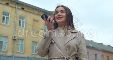 女士使用智能<strong>手机</strong>语音录音<strong>功能</strong>在线在城市街道，与移动助理交谈。 女孩使用