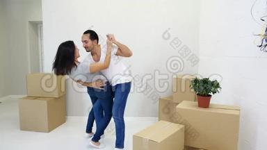 第一次买房的夫妇在客厅里和一堆盒子一起跳舞，一起欢笑，一起享受乐趣。