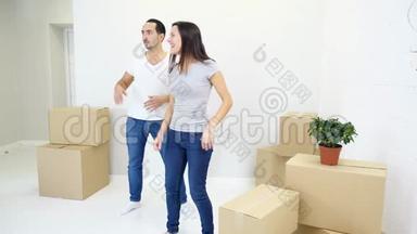 第一次买房的夫妇在客厅里和一堆盒子一起跳舞，一起欢笑，一起享受乐趣。