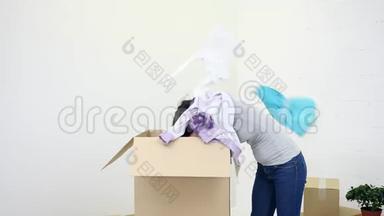 快乐满足的女人收拾纸箱，兴奋地掏出衣服。