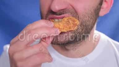 特写，一个男人在吃快餐.. 咬一块鸡肉。 手里拿着金块。 健康饮食的问题