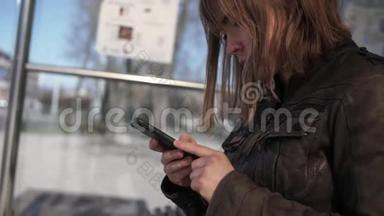 坐在<strong>公交</strong>车站的Youn Women使用智能手机