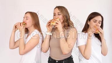 三个女孩吃美味的汉堡。