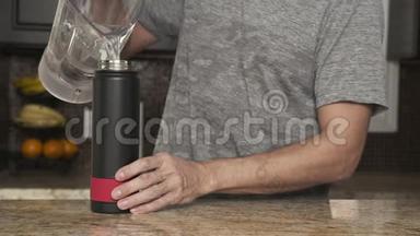 穿着灰色T恤的年轻人在一个漂亮时尚的厨房里用塑料瓶把水<strong>倒</strong>进<strong>热水</strong>瓶
