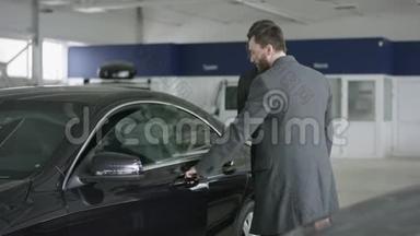 汽车经销商客户坐在车里。 汽车经销商为汽车买家打开了一扇门。 愉快的客户与交易员交谈
