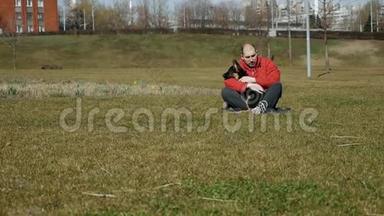 一个男人坐在<strong>草地</strong>上，抱着他的德国牧羊犬在<strong>草地</strong>上。 慢动作