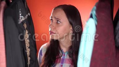 年轻女子紧紧地环视四周，拍打着她的脸颊，思考着如何选择衣柜里的衣服。