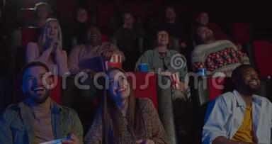 多民族观众在电影院观看滑稽电影的正面景色。 电影中喜剧电影中的人们笑