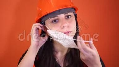 穿工作服的女建筑<strong>工人</strong>在橙色背景上脸上戴医用<strong>口罩</strong>。