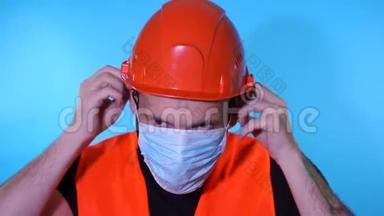 男建筑<strong>工人</strong>穿工作服，在蓝色背景上脸上戴医用<strong>口罩</strong>。