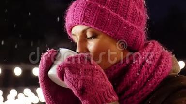 快乐的年轻女子在冬天在户外喝茶