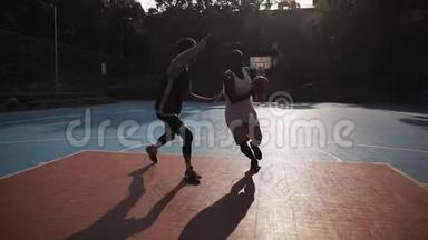 两个年轻的活跃混合种族球员打篮球，弹跳球，一对一在外面，非裔美国人在球上的得分