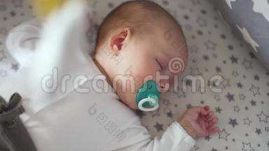<strong>一个</strong>刚出生的婴儿睡在婴儿床上，<strong>嘴</strong>里放着蓝色的奶<strong>嘴</strong>