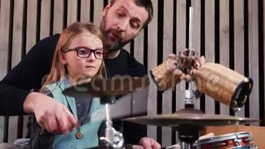 爸爸和女儿一起玩打击乐。 小女孩在家和爸爸一起学鼓。 前景。 打击乐课程