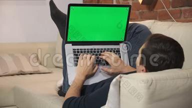桌上的人正在绿色笔记本电脑屏幕上浏览互联网。 在一个光线充足，舒适的公寓里。 一个人在工作