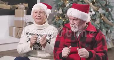积极的白人老年妇女与丈夫坐在圣诞树下，闭着眼睛指望着