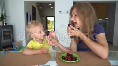 可爱的<strong>妈妈在家</strong>里给她的孩子喂樱桃浆果。 <strong>妈妈</strong>亲儿子