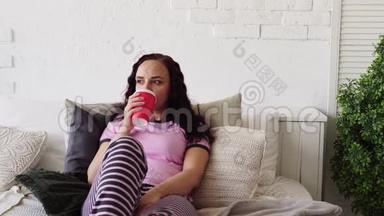 一个年轻的女人在床上<strong>吃</strong>热狗和喝咖啡。 在床上<strong>吃</strong>早餐。 把食物送到你家。 女人<strong>吃东西</strong>