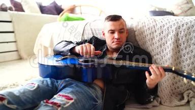 一个胸前有纹身的年轻人在卧室里弹吉他。 希普斯特学会弹吉他。 特写镜头