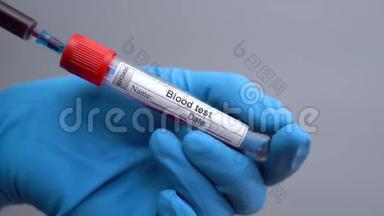 验血。 冠状病毒血液检测的特写注射器填充管。 戴蓝色手术手套的医生将血液注入试管