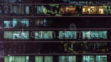 办公室摩天大楼在深夜外景，室内灯亮着，人们在夜间工作