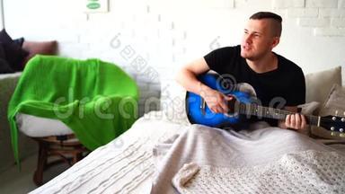 一个胸前有纹身的年轻人在卧室里弹吉他。 希普斯特学会弹吉他。 特写镜头