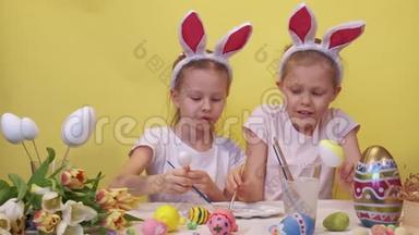 专注的姐妹，兔子耳朵站在桌子附近，调色板和郁金香花束仔细着色鸡蛋，而