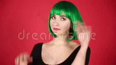 美丽的女孩戴着绿色假发，做着鬼脸，到处都是傻瓜，表达着不同的情感。 视频