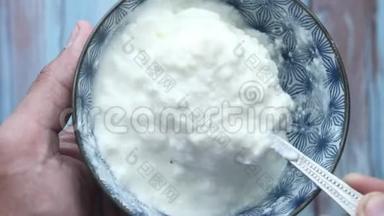 希腊酸奶在一个木制的碗在一个乡村木制的桌子上。
