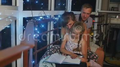 妈妈、<strong>爸爸和女儿</strong>在睡觉前坐在夜窗附近。 <strong>女儿</strong>读了一本大童话书