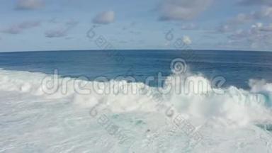 阳光明媚的一天，带着美丽的泡沫滚滚海浪的蓝色海洋鸟瞰