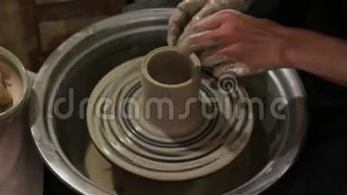主人创造一个白色粘土产品。 主人`用陶工的轮子特写雕刻一件粘土制品。 陶工的茶杯