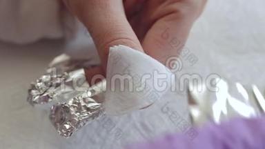 一个年轻的女人做指甲。 把他的手指包在箔纸上，以去<strong>除旧</strong>凝胶。 指甲修指甲