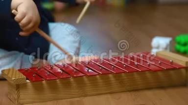 孩子在红色木琴上玩棍子，打击乐器，关门
