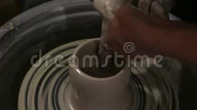 主人创造一个白色粘土产品。 主人`用陶工的轮子特写雕刻一件粘土制品。 陶工的茶杯