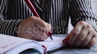 女人在笔记本上写东西。女人的手放在桌子上一个白色的空白笔记本上，为这个话题写了一个计划