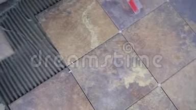在地板上铺瓷砖，主人用梳子把瓷砖粘在瓷砖上