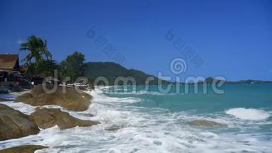 海浪在海滩上的岩石上翻滚。 热带海滩的海岸。 背景中的真菌和棕榈树。 拉麦灯塔