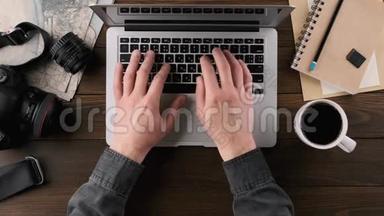 手在笔记本电脑键盘上打字，木制桌子，俯视图