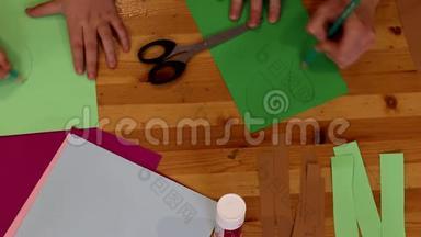 男孩和女孩的手为游戏从纸上剪出数字。 孩子的教育。 设计师工作记录