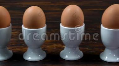 在蛋杯中的蛋杯中，一排煮鸡蛋对着一个带条纹的蛋杯中的单个鸡蛋，微笑着